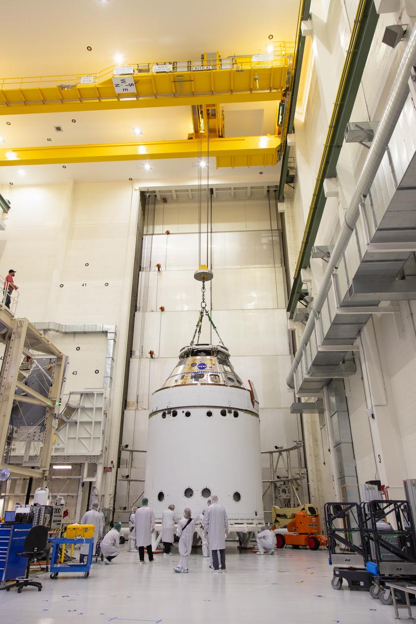 A crane returns NASA’s Artemis II Orion spacecraft to the Final Assembly and System Testing (FAST) cell inside the Neil A. Armstrong Operations and Checkout Building at NASA’s Kennedy Space Center in Florida on Friday, March 21, 2025, following installation of four solar array winds and adapter jettison fairings. Once complete, the Orion spacecraft will be transported to other facilities for fueling and integration with its launch abort system before arriving at the Vehicle Assembly Building where it will be stacked atop the SLS (Space Launch System) by NASA’s Exploration Ground System team at the Vehicle Assembly Building in preparations for Artemis II launch operations.